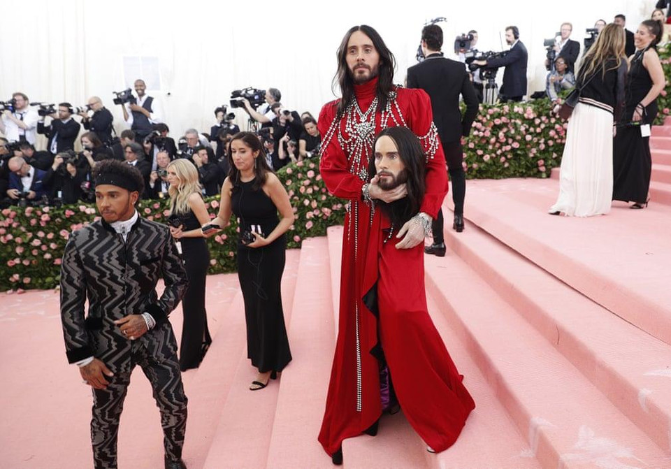 Jared Leto mặc một chiếc váy Gucci làm từ lụa đỏ, mang theo một cái đầu làm từ sáp mô phỏng gương mặt anh. (Nguồn: Guardian)