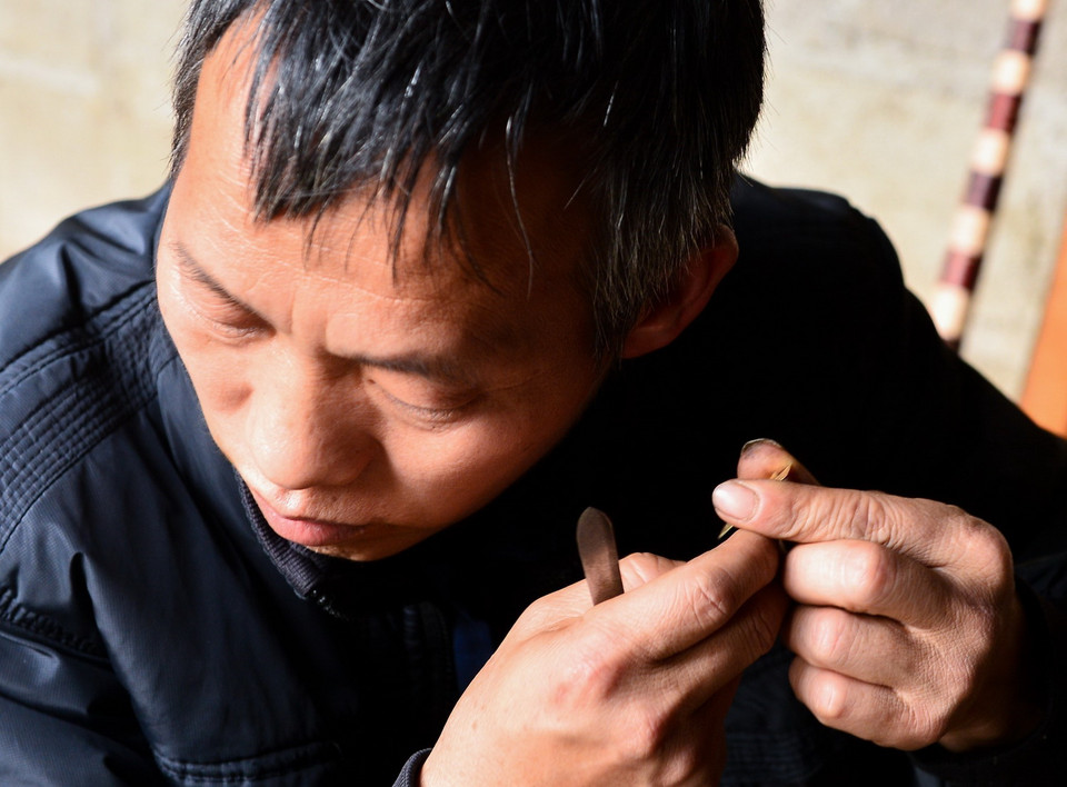  Nghệ nhân phải thẩm âm lá đồng trước khi gắn lên ống trúc. (Ảnh: Nam Thái/TTXVN)