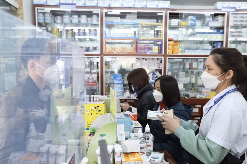 Nhân viên cửa hàng thuốc Long Châu giải thích cho khách về thuốc Molnupiravir điều trị COVID-19. (Ảnh: Minh Quyết/TTXVN)