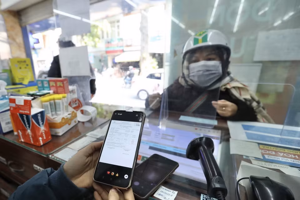 Nhân viên bán thuốc kiểm tra thông tin xác nhận F0 của khách đến mua thuốc thuốc Molnupiravir điều trị COVID-19 tại cửa hàng thuốc Long Châu, Hà Nội. (Ảnh: Minh Quyết/TTXVN)
