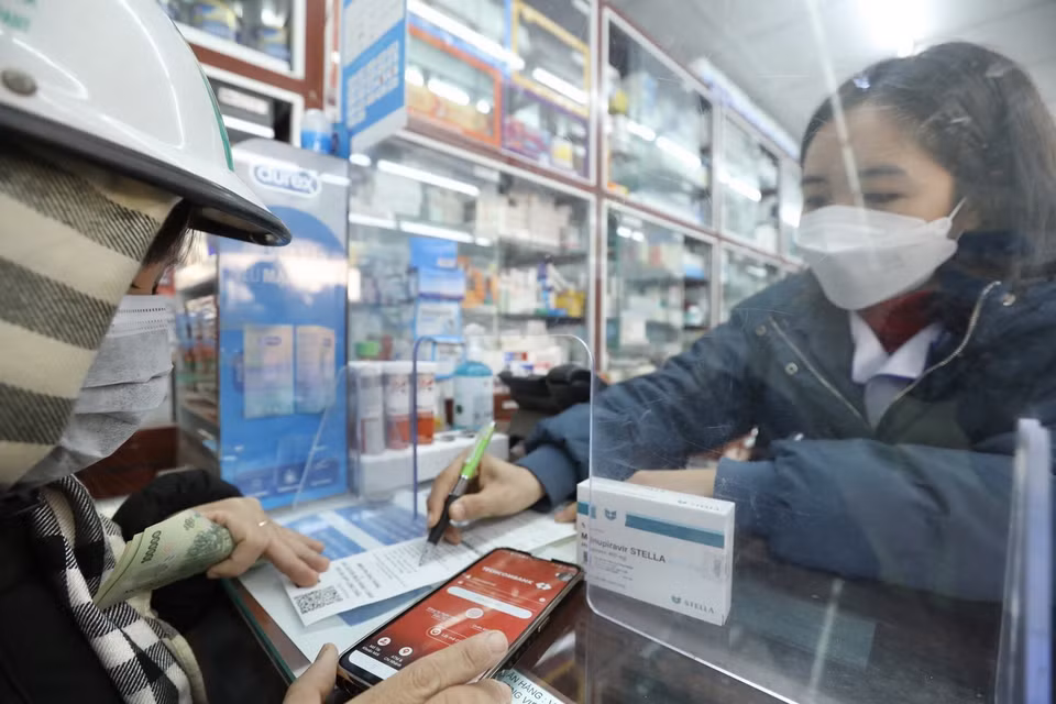 Chị Vân Anh ở Đông Ngạc, Hà Nội, đi mua thuốc Molnupiravir điều trị cho 2 người thân bị mắc COVID-19. (Ảnh: Minh Quyết/TTXVN)