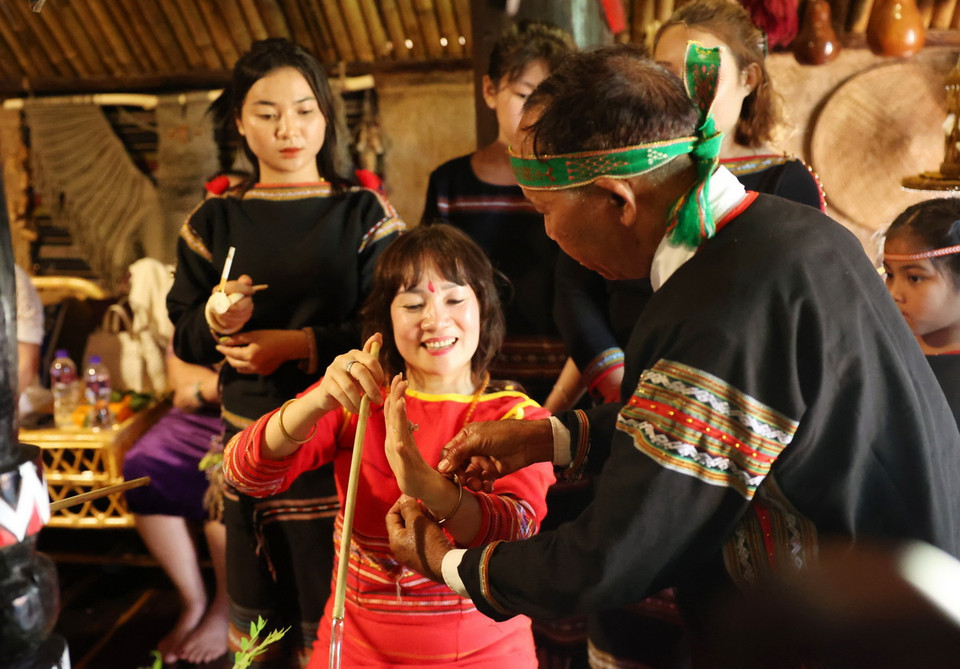 Thầy cúng đeo vòng tay cho chủ nhà để cầu mong sức khỏe và mọi điều tốt đẹp. (Ảnh: Tuấn Anh/TTXVN)