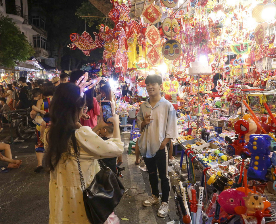 Các bạn trẻ chụp ảnh lưu niệm tại phố Hàng Mã. (Ảnh: Tuấn Đức/TTXVN)