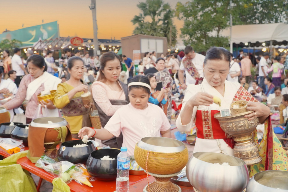Một gia đình đưa con nhỏ đến tham dự nghi lễ Xaybat tại khuôn viên Boun Thatluang. (Ảnh: Đỗ Bá Thành/Vietnam+)