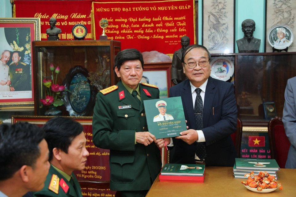 Cựu Nhà báo Trần Tuấn tặng sách ảnh "Đại tướng Võ Nguyên Giáp trong lòng dân" cho người nhà gia đình Đại tướng và các đại biểu. (Ảnh: Thành Đạt/TTXVN)