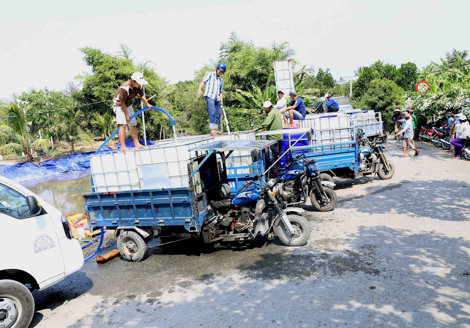 Người dân trên địa bàn xã Thanh Hòa, thị xã Cai Lậy đến lấy nước ngọt miễn phí tại điểm cung cấp nước ngọt cầu Ông Thiệm. (Ảnh: Vũ Sinh/TTXVN)