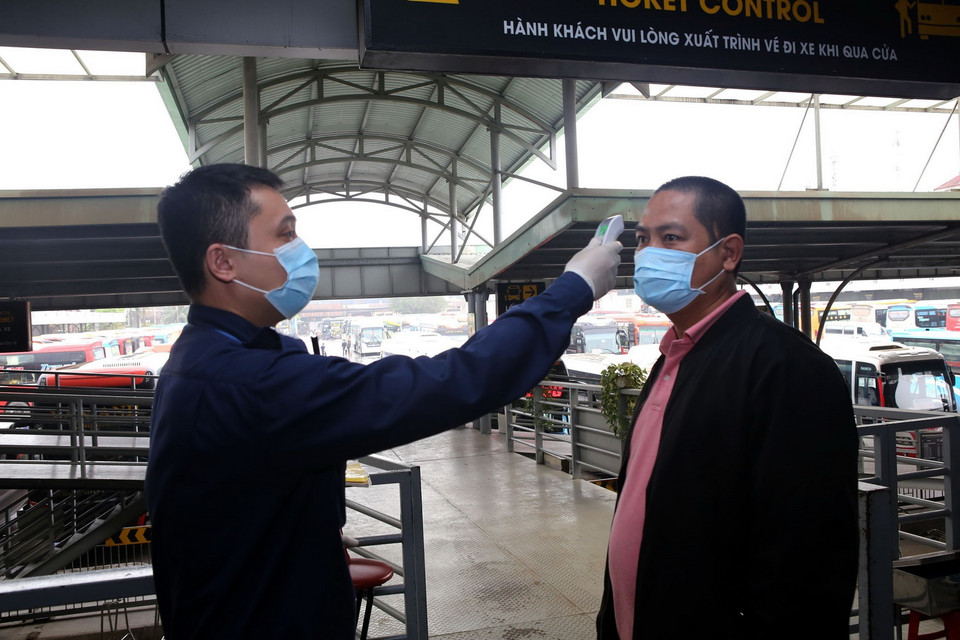 Đo thân nhiệt tại cửa soát vé tại bến xe Nước Ngầm, Hà Nội. (Ảnh: Danh Lam/TTXVN)