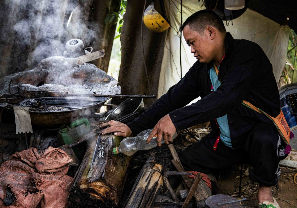Thợ rèn người Mông dùng thân cây chuối tươi để tôi dao. (Ảnh: Xuân Tư/TTXVN)