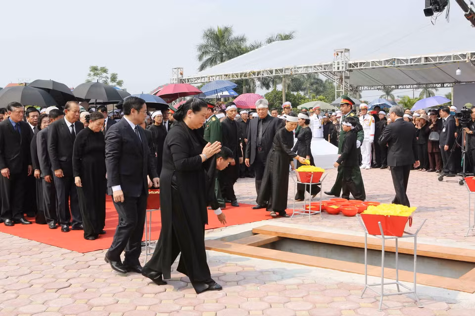 Các đồng chí lãnh đạo, nguyên lãnh đạo Đảng, Nhà nước, Mặt trận Tổ quốc Việt Nam thả những nắm đất đầu tiên xuống huyệt mộ nguyên Tổng Bí thư Đỗ Mười. (Ảnh: Dương Giang/TTXVN)