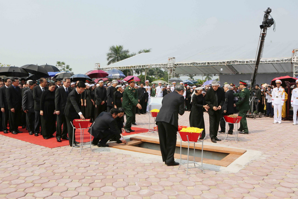 Các đồng chí lãnh đạo, nguyên lãnh đạo Đảng, Nhà nước, Mặt trận Tổ quốc Việt Nam thả những nắm đất đầu tiên xuống huyệt mộ nguyên Tổng Bí thư Đỗ Mười. (Ảnh: Dương Giang/TTXVN)