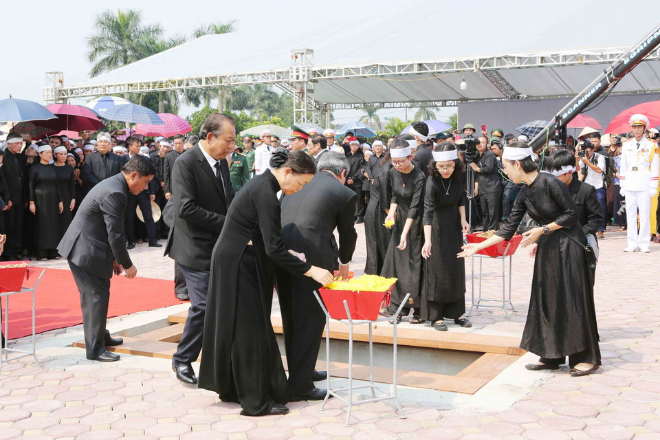 Các đồng chí lãnh đạo, nguyên lãnh đạo Đảng, Nhà nước, Mặt trận Tổ quốc Việt Nam thả những nắm đất đầu tiên xuống huyệt mộ nguyên Tổng Bí thư Đỗ Mười. (Ảnh: Dương Giang/TTXVN)