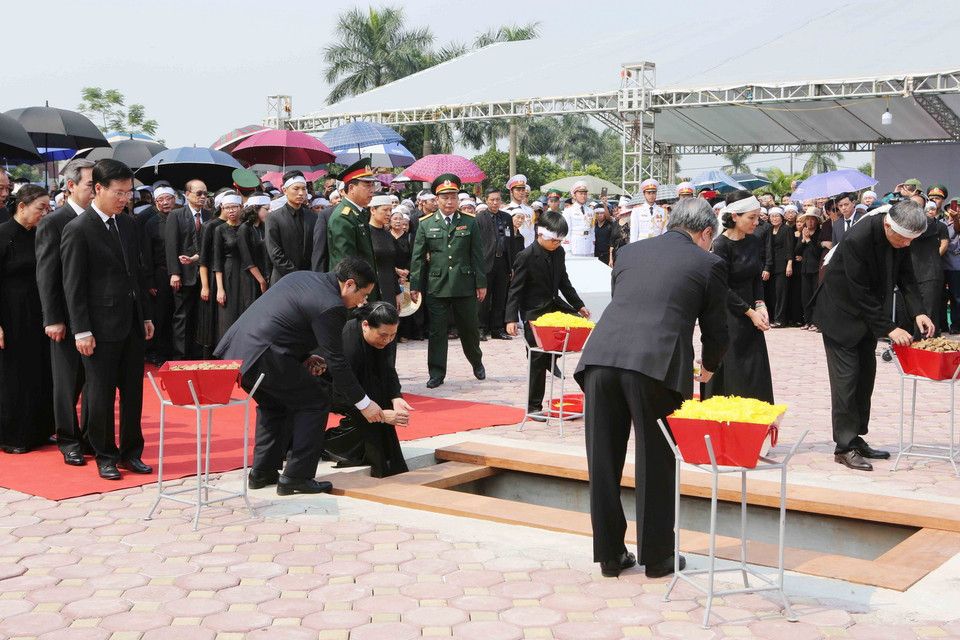 Các đồng chí lãnh đạo, nguyên lãnh đạo Đảng, Nhà nước, Mặt trận Tổ quốc Việt Nam thả những nắm đất đầu tiên xuống huyệt mộ nguyên Tổng Bí thư Đỗ Mười. (Ảnh: Dương Giang/TTXVN)