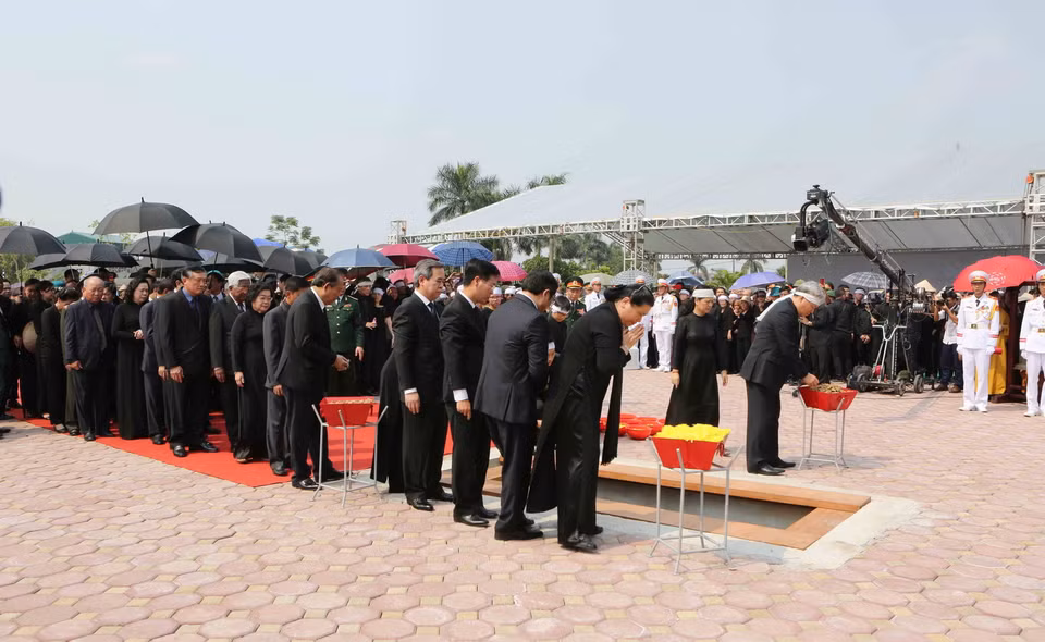 Các đồng chí lãnh đạo, nguyên lãnh đạo Đảng, Nhà nước, Mặt trận Tổ quốc Việt Nam thả những nắm đất đầu tiên xuống huyệt mộ nguyên Tổng Bí thư Đỗ Mười. (Ảnh: Dương Giang/TTXVN)