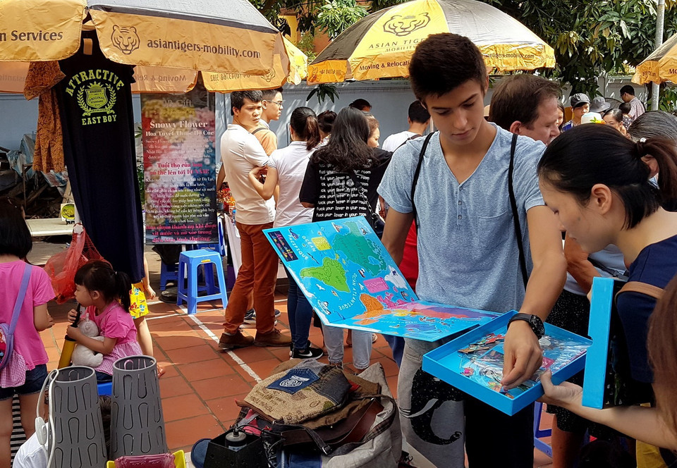 Cậu bé đang hướng dẫn sử dụng bộ đồ vừa học vừa chơi của trẻ em còn nguyên hộp cho người hỏi mua. (Ảnh: Ngọc Hà/TTXVN)