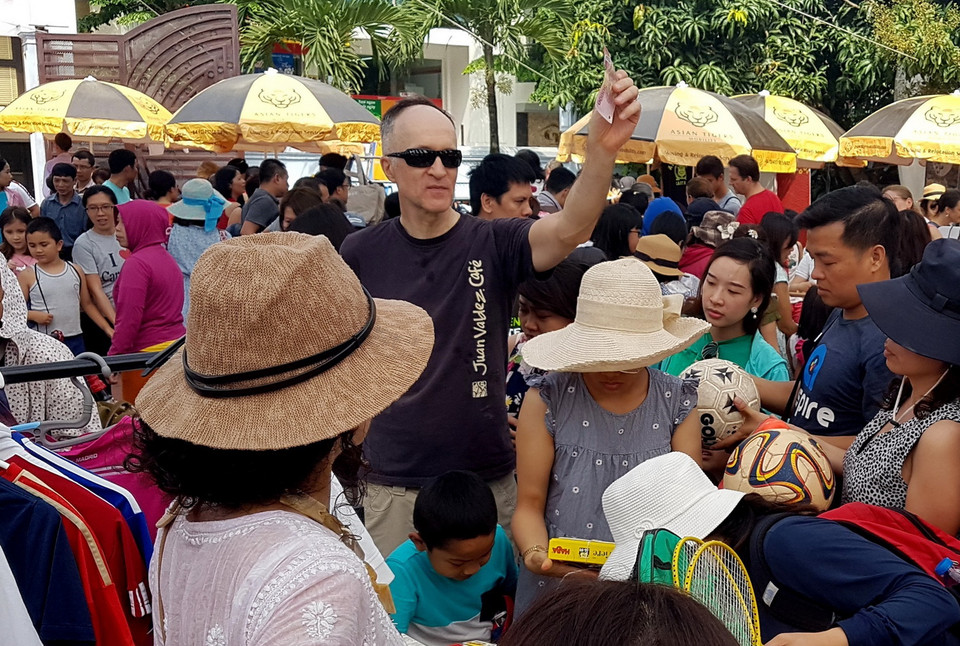  Ông bố bán hàng và thu tiền giúp cậu con trai. (Ảnh: Ngọc Hà/TTXVN)