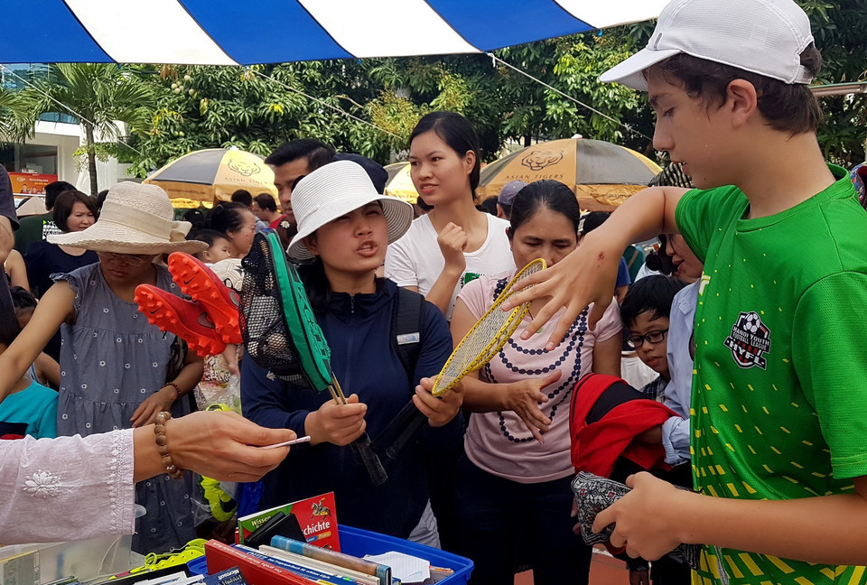  Hàng của gia đình cậu bé này bán rất chạy, cậu luôn tay, luôn miệng tư vấn và thu tiền. (Ảnh: Ngọc Hà/TTXVN)