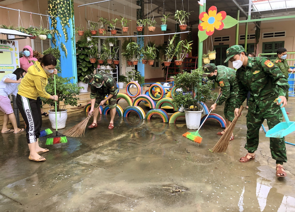  Lực lượng cán bộ, chiến sỹ Đồn Biên phòng cửa khẩu cảng Quy Nhơn phối hợp với chính quyền địa phương giúp trường Mầm non dọn dẹp vệ sinh, khắc phục hậu quả lũ lụt. (Ảnh: Nguyên Linh/TTXVN)