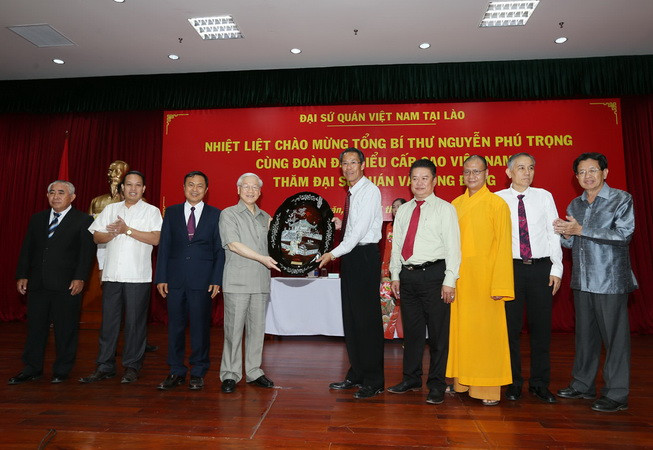 Tổng Bí thư Nguyễn Phú Trọng tặng quà lưu niệm cho đại diện cộng đồng người Việt. (Ảnh : Trí Dũng/TTXVN) Tổng Bí thư gặp cán bộ Đại sứ quán, cộng đồng Việt Nam tại Lào ảnh 2