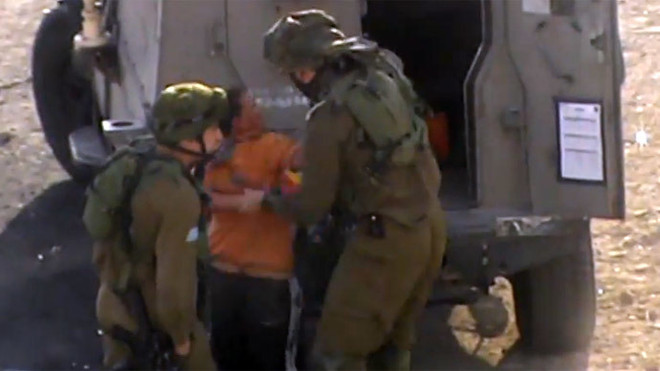 Lính Israel còng tay cậu bé Palestine (Nguồn: RT) Video lính Israel còng tay cậu bé Palestine thiểu năng gây phẫn nộ ảnh 1
