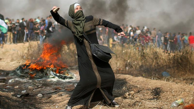 Một phụ nữ người Palestine chống trả quân đội Israel. (Nguồn: Reuters) Bạo lực tiếp diễn tại Dải Gaza, hàng chục người thương vong ảnh 1