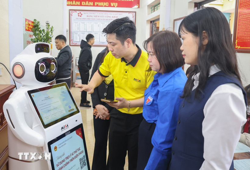 Cán bộ Trung tâm phục vụ hành chính công xã Quỹ Nhất hướng dẫn người dân thao tác trên Robot Lễ tân AI. (Ảnh: Công Luật/TTXVN)