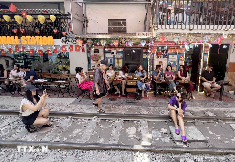 Nhiều du khách nước ngoài tranh thủ "check-in" tại "phố càphê đường tàu" ở Hà Nội. (Ảnh: Thành Phương/TTXVN)