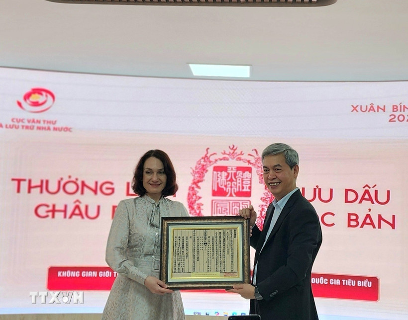 Cục trưởng Cục Văn thư và Lưu trữ nhà nước Đặng Thanh Tùng tặng bà Elena Bezdetko, Phu nhân Đại sứ Nga tại Việt Nam bản in dập từ Mộc bản về Quốc hiệu Việt Nam. (Ảnh: Chu Thanh Vân/TTXVN)