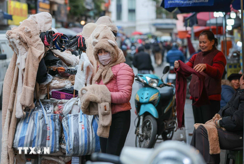 Người lao động, bán hàng trên phố che chắn kỹ chống rét. (Ảnh: Hoàng Hiếu/TTXVN)