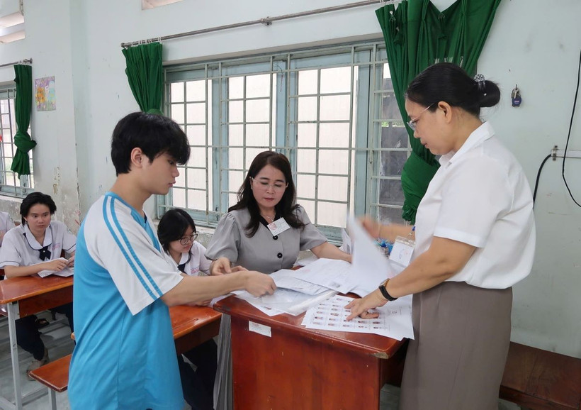 Cán bộ coi thi hướng dẫn thí sinh kiểm tra thông tin cá nhân. (Ảnh: Thu Hoài/TTXVN)