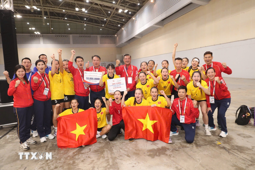 Các cầu thủ và ban huấn luyện tuyển bóng ném nữ Việt Nam ăn mừng với chiếc huy chương Vàng. (Ảnh: TTXVN phát)