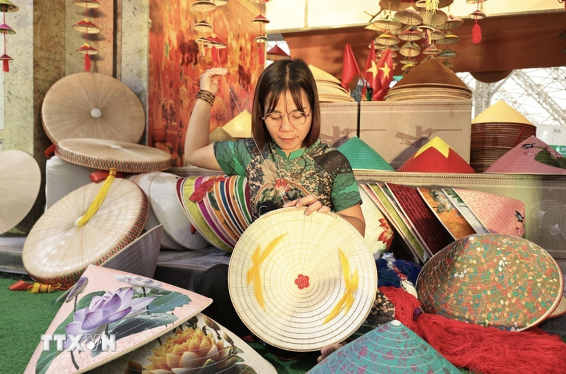 Nghệ nhân Phạm Thị Vấn làng Chuông, Hà Nội biểu diễn làm nón tại hội chợ. (Ảnh: Trần Việt/TTXVN)