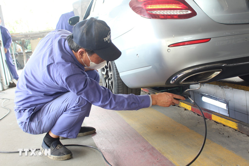 Nhân viên đăng kiểm thực hiện thao tác trong quy trình kiểm định khí thải. (Ảnh: Nguyễn Thắng/TTXVN)