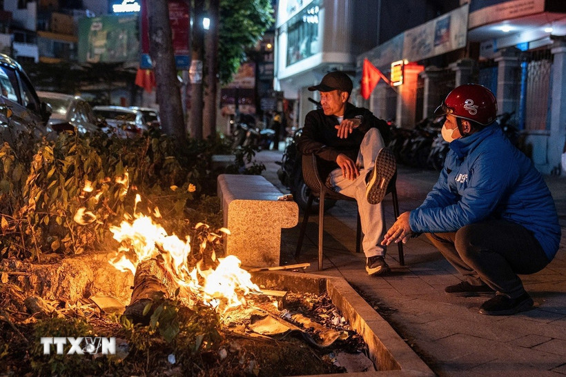 Người dân đốt lửa sưởi ấm trên hè phố. (Ảnh: Phạm Tuấn Anh/TTXVN)