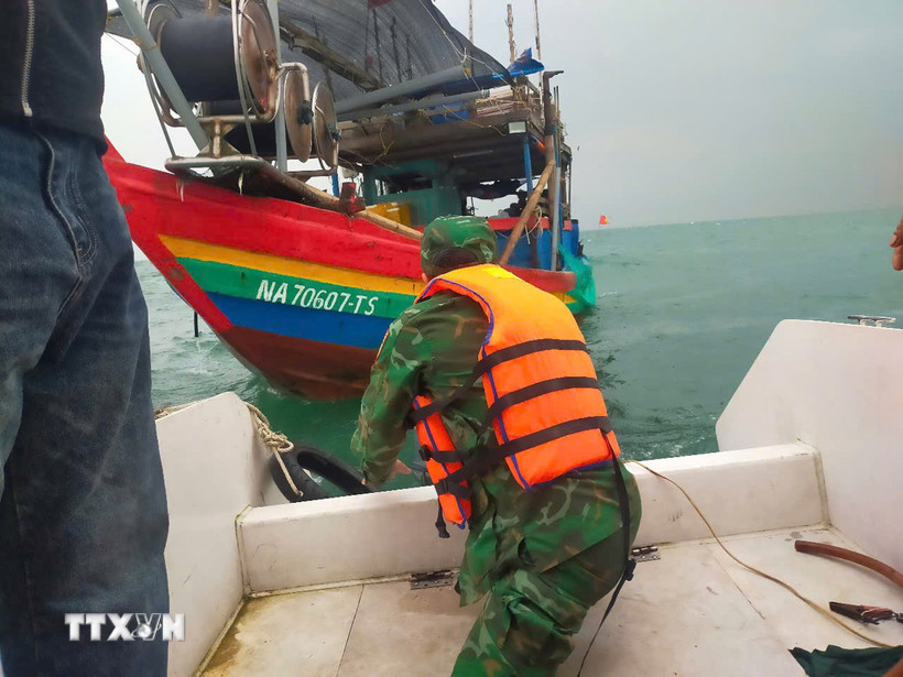 Lực lượng cứu nạn của Đồn Biên phòng Diễn Thành tiếp cận vị trí tàu cá bị chìm, đưa 3 ngư dân gặp nạn lên ca nô an toàn. (Ảnh: TTXVN phát)