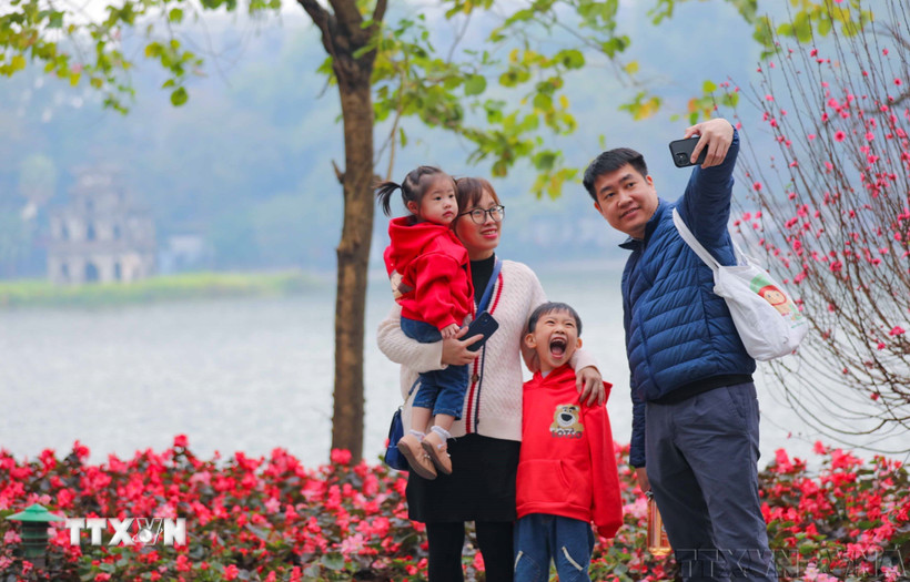 Cả gia đình cùng nhau ghi lại khoảnh khắc của mùa Xuân bên hồ Gươm. (Ảnh: Thanh Tùng/TTXVN)