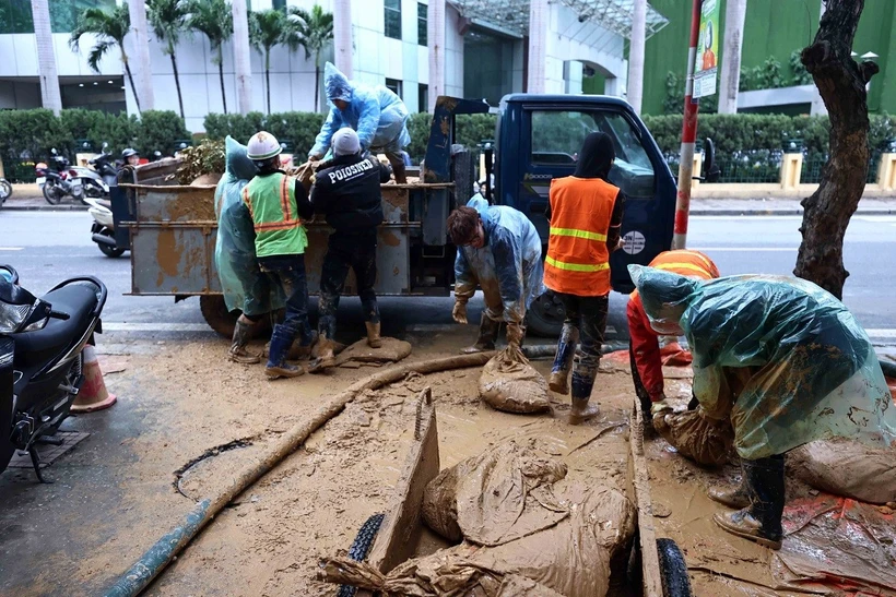 Công nhân Công ty vệ sinh môi trường đô thị Hà Nội tiếp tục dọn dẹp những vật dụng dùng trong lúc xử lý bùn nhão phun trào (ảnh chụp chiều 23/2).( Ảnh: An Đăng/TTXVN)