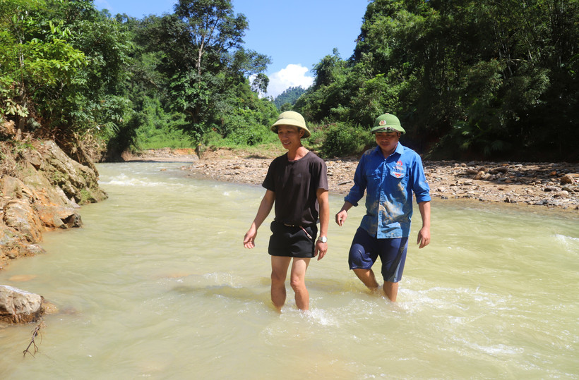 Anh Lương Văn Ủn, Phó trưởng bản Na Ngân (đi sau) cùng người dân trong bản vượt suối, đi khảo sát, xem xét những vết nứt trên đồi và núi phía sau bản, trên khu vực thượng nguồn suối Nậm Ngân. (Ảnh: Xuân Tiến/TTXVN)