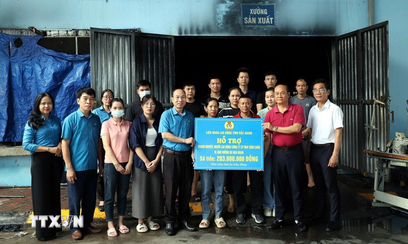 Phó Chủ tịch Liên đoàn Lao động tỉnh Bắc Giang Lê Đức Thọ trao kinh phí hỗ trợ cho doanh nghiệp, người lao động Công ty Cổ phần May Năm Châu. (Ảnh: Đồng Thúy/TTXVN)