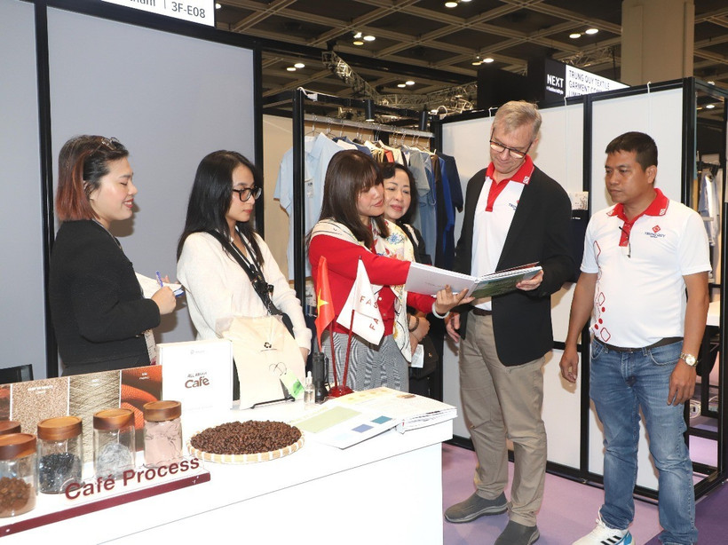 Khách hàng tìm hiểu thông tin về các sản phẩm thời trang làm từ bã càphê và sợi dứa của doanh nghiệp Việt Nam. (Ảnh: Xuân Vịnh/TTXVN)