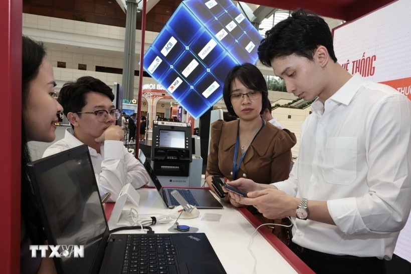 Hướng dẫn khách hàng làm sử dụng dịch vụ online tại Hội nghị Chuyển đổi Số ngành Ngân hàng năm ngoái. (Ảnh: Trần Việt/TTXVN)