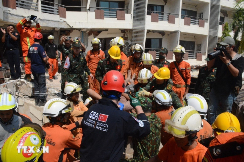 Lực lượng cứu hộ của Việt Nam, Myanmar và Thổ Nhĩ Kỳ đưa nạn nhân ra xe cứu thương. (Ảnh: Vũ Hùng/TTXVN phát)