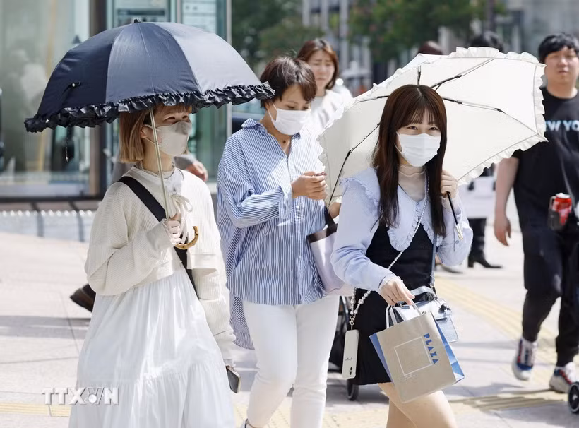 Người dân di chuyển trên đường phố dưới trời nắng nóng tại Fukuoka (Nhật Bản). (Ảnh: Kyodo/TTXVN)