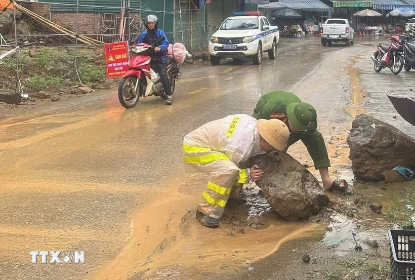 Cảnh sát giao thông ở một địa phương miền núi phía Bắc khắc phục hiện tượng sạt lở đất đá do mưa lớn trong thời gian gần đây. (Ảnh: TTXVN phát)