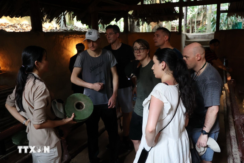 Du khách nước ngoài nghe thuyết minh về các loại vũ khí tại hầm xưởng công binh. (Ảnh: Thu Hương/TTXVN)