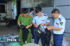 Lực lượng chức năng kiểm tra các sản phẩm may mặc tại xưởng. (Ảnh: Đức Phương/TTXVN)