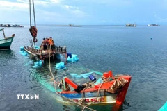 Tàu cá BT 93185 TS bị nạn trên biển được cán bộ, chiến sỹ Đồn Biên phòng Hòn Chuối và ngư dân hỗ trợ lai dắt vào bờ. (Ảnh: Hoàng Tá/TTXVN)