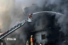 Lính cứu hỏa nỗ lực dập lửa vụ cháy tòa nhà Trung tâm thương mại ở Karachi, Pakistan ngày 18/1/2026. (Ảnh: THX/TTXVN)