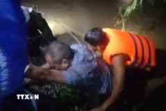 Lực lượng cứu hộ xã Đồng Xuân, tỉnh Đắk Lắk, phối hợp với người dân ứng cứu 2 nạn nhân. (Ảnh: TTXVN phát)