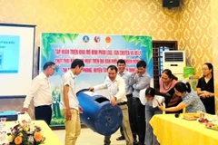Tiến sỹ Võ Anh Khuê (thứ 3, bên trái sang) hướng dẫn sử dụng thùng ủ rác có thể tích 220 lít cho người dân ở thị trấn Phú Phong, huyện Tây Sơn, tỉnh Bình Định. (Ảnh: Vusta)