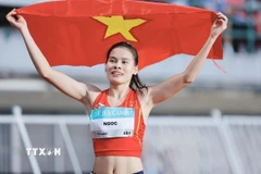 Vận động viên điền kinh Nguyễn Thị Ngọc với lá cờ Tổ quốc sau khi giành huy chương Vàng chạy 400m nữ tại SEA Games 33. (Ảnh: Minh Quyết/TTXVN)
